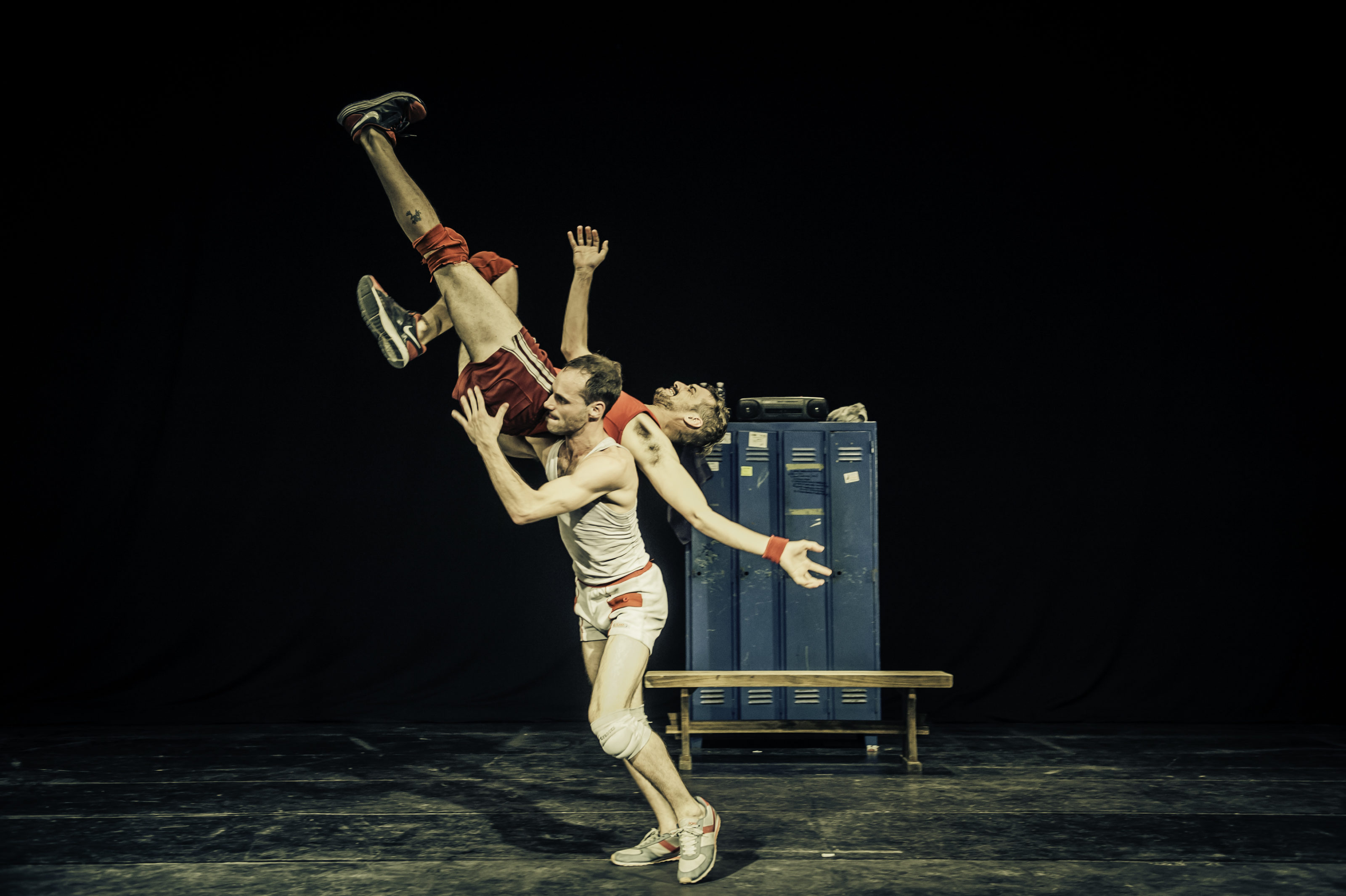 An artist carries another on his shoulder and seems to be about to throw him on the floor.