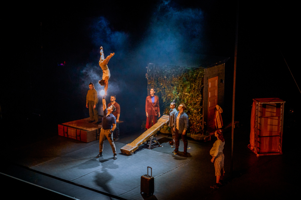 From the show: all the performers are looking at the man in the middle, who is holding a…
