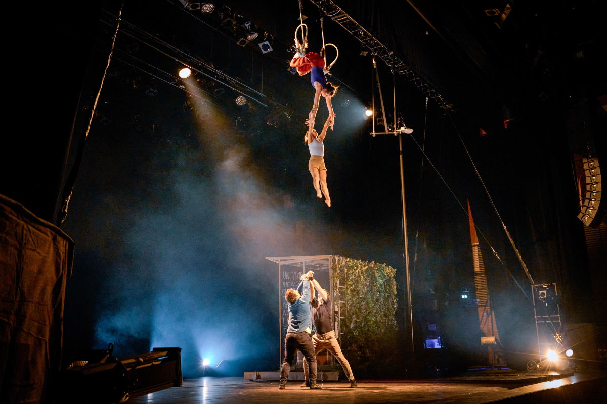 From the show: a woman hangs upside down from the ceiling on a trapeze and catches anothe…